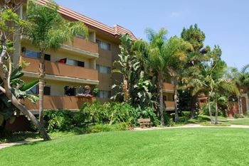 A building with a balcony and a green lawn in front.